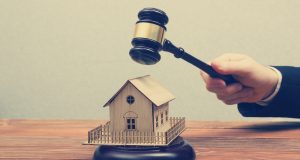 Auction, Real Estate concept. Hand with judge gavel and house model